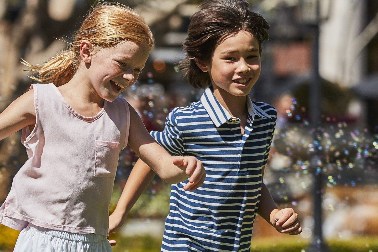 A teen boy and a girl running in same direction with smile