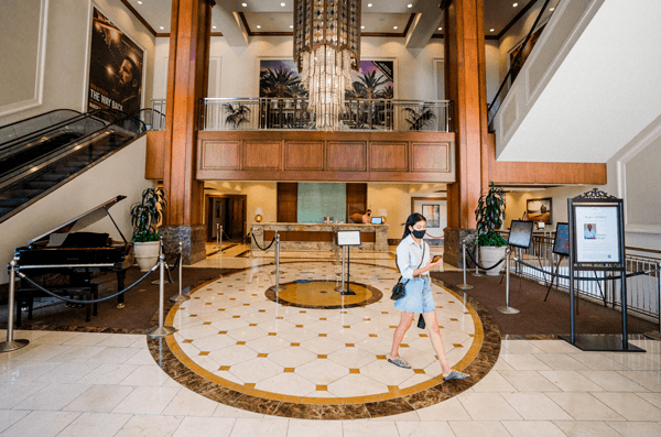 A lobby withe a black piano and a girl walking