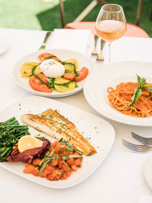 Food options, spaghettis, fish filet with vegetables and a tomato salad with mozzarella