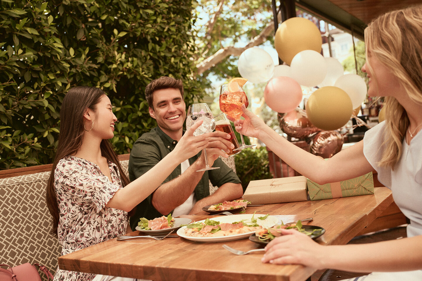 A guy with two girls enjoying their breakfast and their drinks on the table